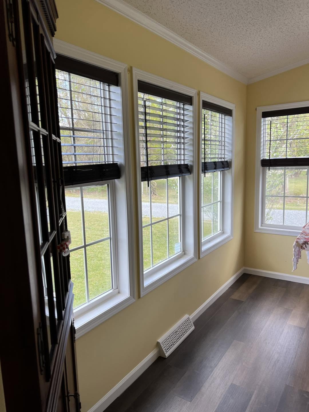 Sunroom with a wall of new windows and dark plank flooring